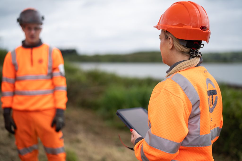 Woman in high vis instructing a team also in PPE workwear.